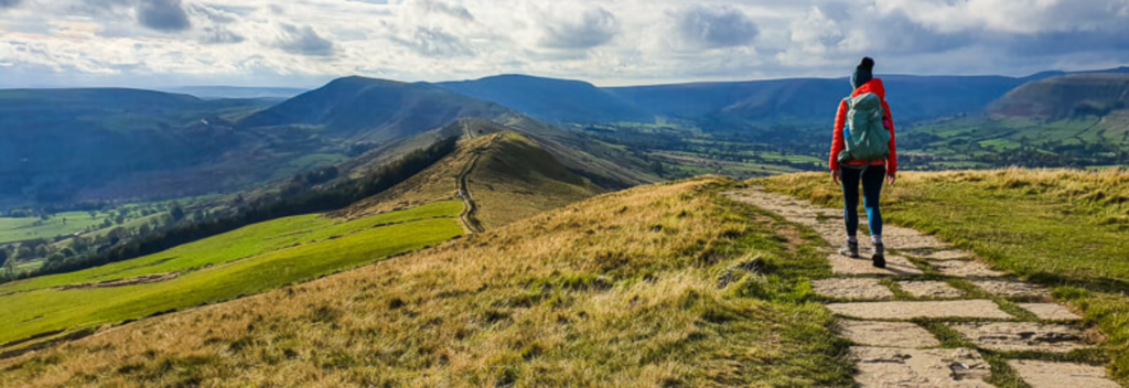 man walking on a path with mountain in the background.