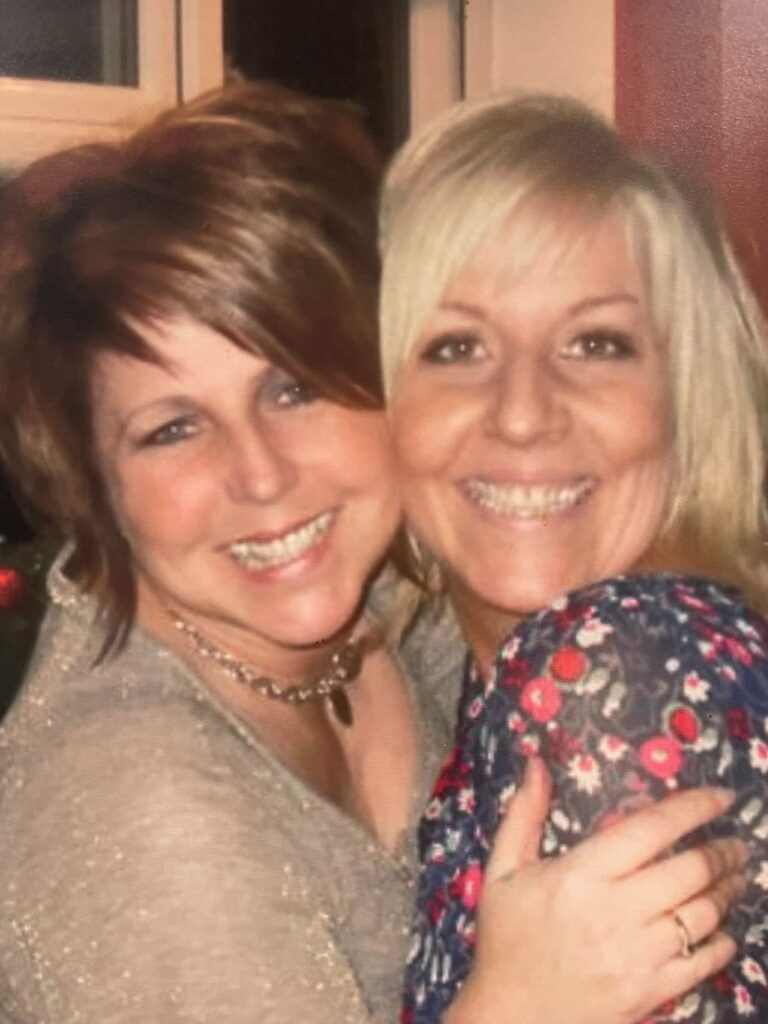Two ladies hugging and smiling.